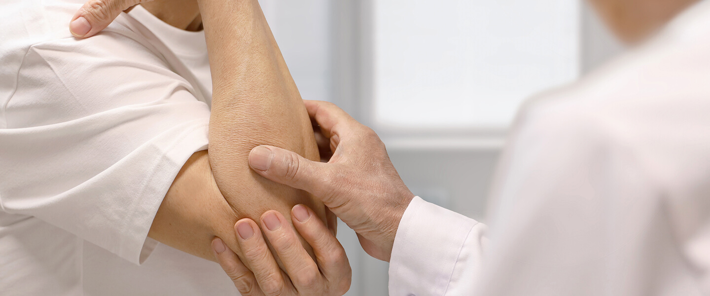 Close-up of a doctor inspecting a man's elbow.